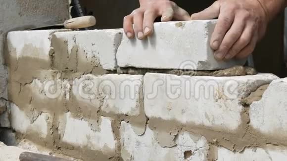 男建造商在水泥和立墙上铺设白砖人类的双手把建筑砖铺在近景上视频的预览图