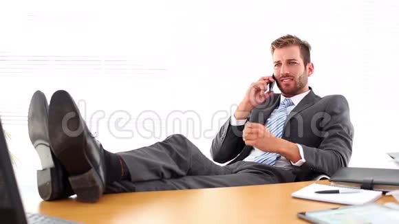 放松的商人把脚放在电话上说话视频的预览图
