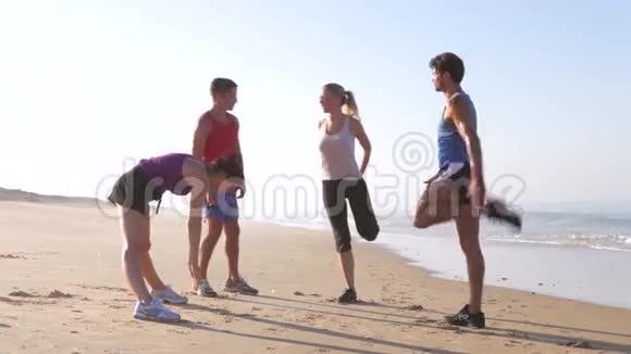 四个人在沙滩上锻炼前热身视频的预览图