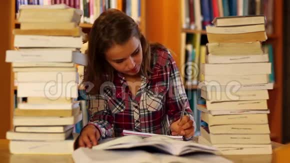 专心致志的学生在图书馆里学习和记笔记周围是书视频的预览图