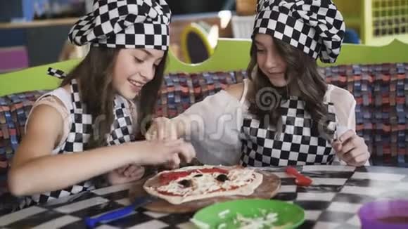 两个穿制服的快乐女孩在4K咖啡馆的大师班做披萨视频的预览图