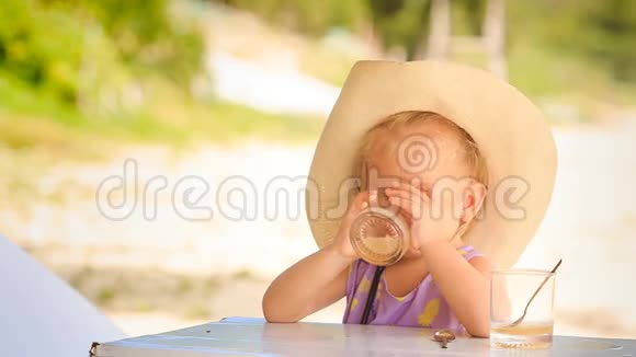 戴帽子的小金发女孩喝玻璃汁视频的预览图