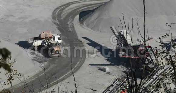 采石场的推土机把一块石头装到一辆自卸卡车的车身上一辆黄色的推土机在一个采石场工作装载一个自卸汽车视频的预览图