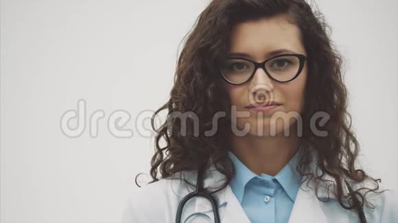 年轻漂亮的女医生穿着医用礼服在这段时间里它是在灰色的背景上握在手中视频的预览图