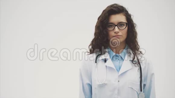 年轻漂亮的女医生穿着医用礼服在这段时间里它是在灰色的背景上握在手中视频的预览图