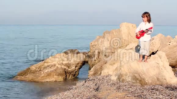 小女孩站在岩石上弹吉他视频的预览图