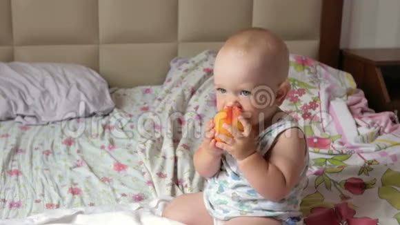 一个漂亮的婴儿在床上早餐吃桃子他撕下一块放进嘴里视频的预览图