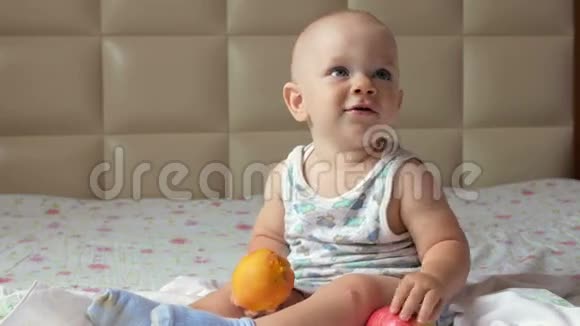 一个漂亮的婴儿在床上早餐吃桃子他撕下一块放进嘴里视频的预览图