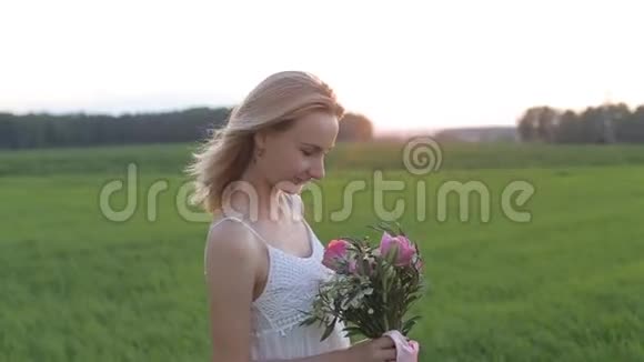 美丽的女人在田野里日落时鲜花盛开视频的预览图