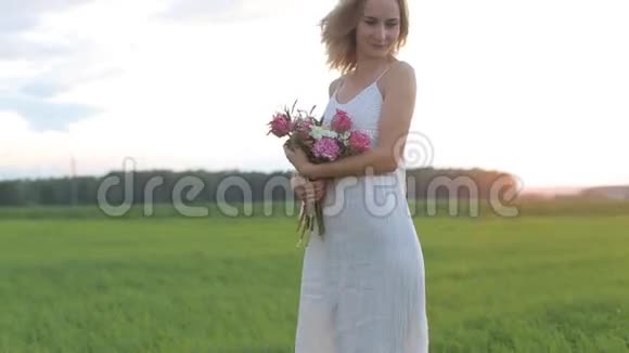 美丽的女人在田野里日落时鲜花盛开视频的预览图