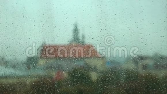 窗玻璃上的雨滴背景中的离焦建筑物视频的预览图