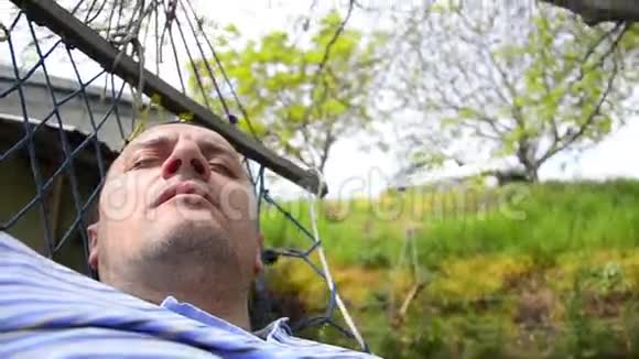 男人睡在吊床上打哈欠视频的预览图