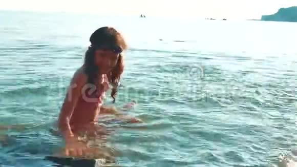 小女孩用石头和石头在海里洗澡少女生活方式女儿在海浪中游泳视频的预览图