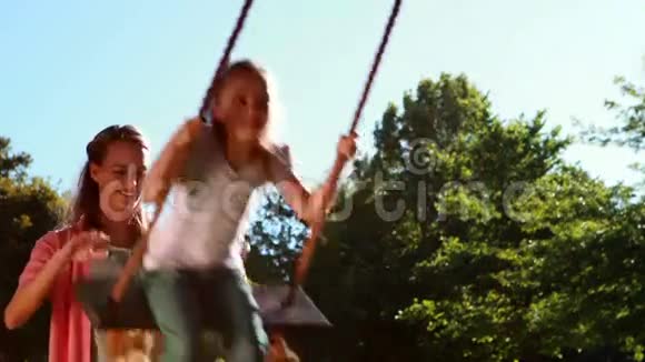 小女孩在公园里被妈妈推着荡秋千视频的预览图