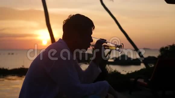 坐在沙滩上喝啤酒的人日落时分视频的预览图