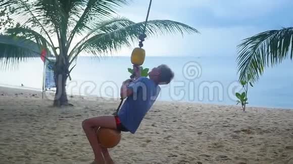 那个快乐的孩子在海滩上荡秋千热带岛屿视频的预览图