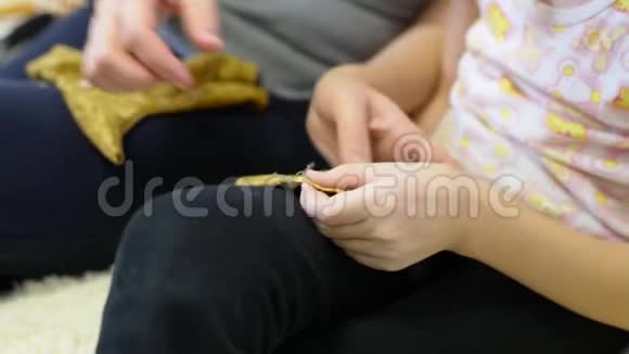 妈妈用针线来教她的女儿一个可爱的女人和她的女儿缝一件洋娃娃的衣服视频的预览图