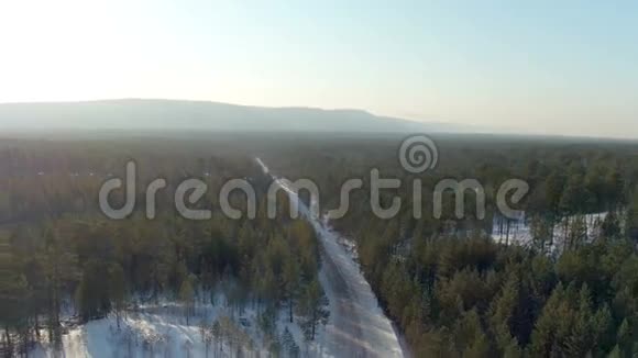 冬季景观背景下针叶林冬季道路空中拍摄视频的预览图