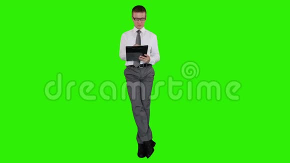 年轻的商人戴着眼镜在剪贴板上扭动坐着绿色屏幕股票录像视频的预览图
