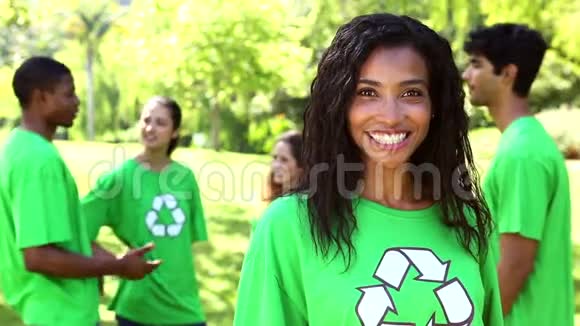 快乐的环保活动家微笑着与她身后的团队视频的预览图
