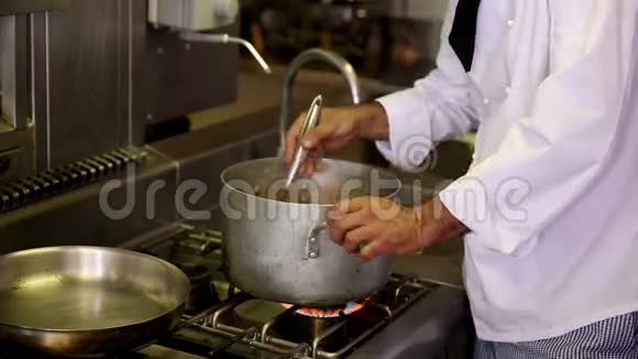英俊的厨师搅拌一大锅视频的预览图