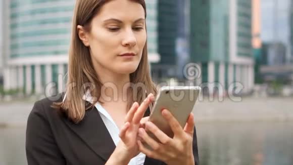 在市中心使用智能手机的女商人职业女性浏览聊天阅读新闻视频的预览图