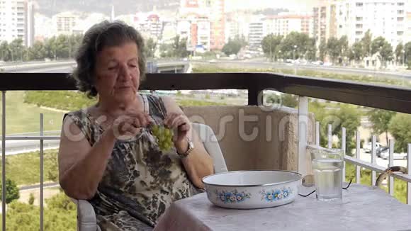 在阳台上吃葡萄的老退休妇女视频的预览图