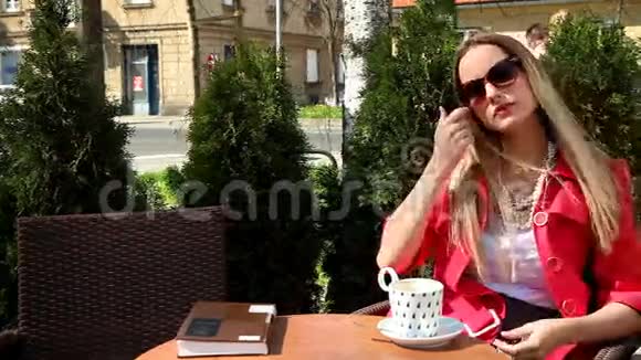 年轻的金发女人坐在咖啡店里喝饮料视频的预览图