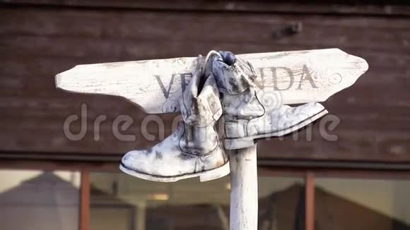 一双白色的旧靴子挂在木制的名牌上在夏日里晃动视频的预览图