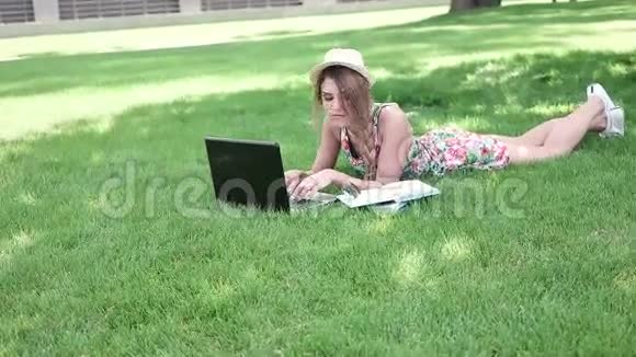 大学生躺在草地上用笔记本电脑工作视频的预览图