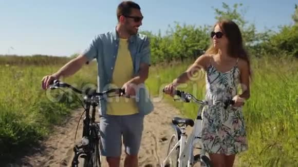 快乐的年轻夫妇骑着自行车在夏天散步视频的预览图