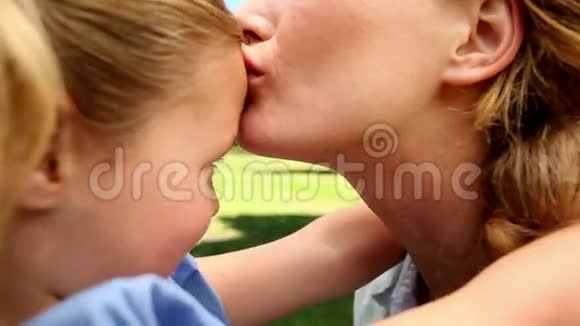 快乐的母亲在公园里亲吻她的小女孩视频的预览图