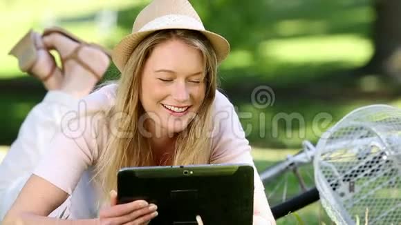 一个漂亮的女孩在公园的自行车旁使用平板电脑视频的预览图