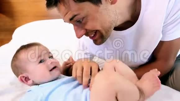 快乐的父亲在床上搔痒他的小儿子视频的预览图
