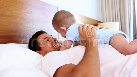 快乐的父亲抱着小儿子躺在床上视频的预览图