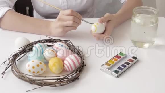 用手和画笔用水彩颜料为复活节彩蛋巢和花环视频的预览图