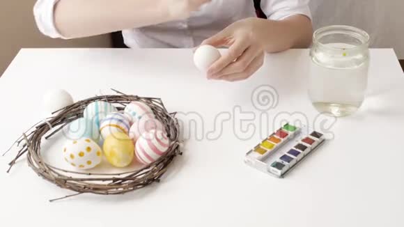 用手和画笔用水彩颜料为复活节彩蛋巢和花环视频的预览图