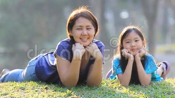 阳光明媚的夏日公园草地上快乐的亚洲母女视频的预览图