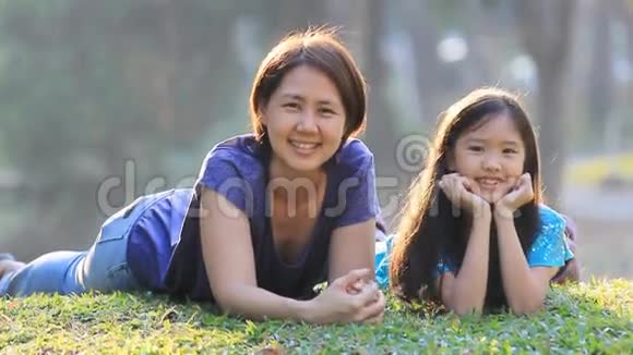 亚洲母女在公园阳光明媚的夏日草地上视频的预览图