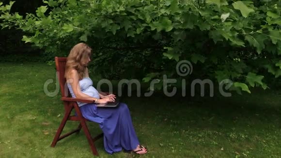 在郁金香树下用电脑工作的孕妇视频的预览图