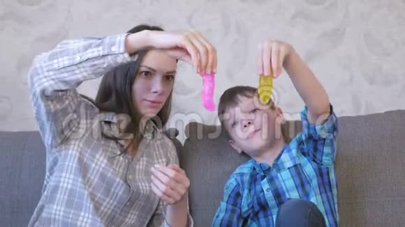 快乐的妈妈和儿子坐在沙发上玩黏液伸展的黏液视频的预览图