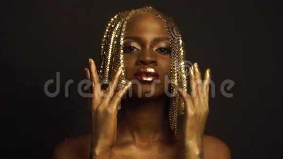 黑人工作室背景下华丽的金色化妆和头饰的非裔美国妇女超现实肖像视频的预览图