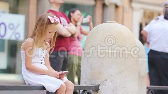 可爱的小女孩与智能手机温暖的一天户外欧洲城市视频的预览图