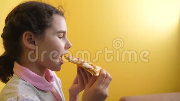 快乐的小女孩吃一片披萨的概念十几岁的孩子饿了吃一片披萨慢生活方式慢生活方式视频的预览图