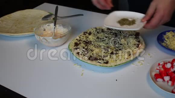 准备披萨一个男人用蘑菇和奶酪为比萨饼洒上牛至基地视频的预览图