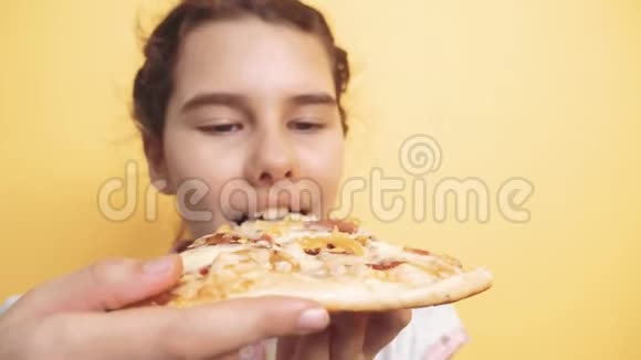 快乐的小女孩吃一片披萨的概念十几岁的孩子饿了吃一片披萨慢动作视频披萨饼视频的预览图
