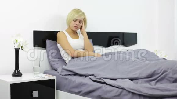 生病的年轻女子在家卧室吃药视频的预览图