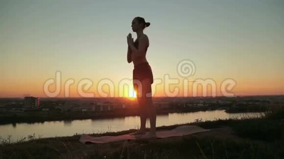 日落时分在公园里练习瑜伽的女人倒回去摆个姿势视频的预览图