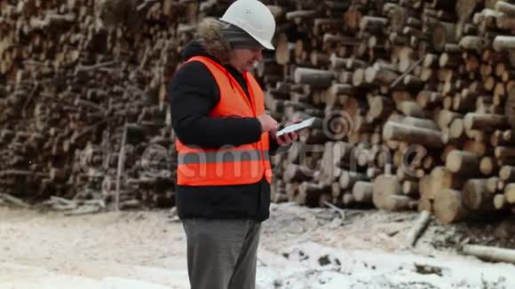 冬季使用平板电脑接近成堆原木的工程师视频的预览图