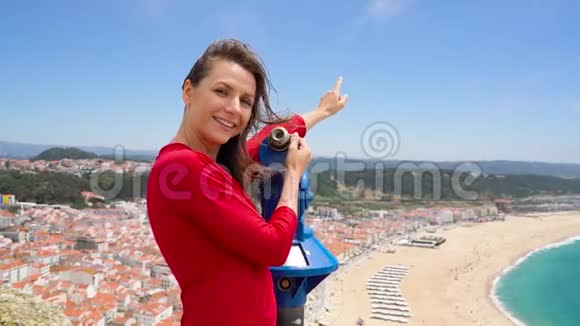 葡萄牙拿撒勒市的女游客在高山上用硬币付费望远镜观看城市风景视频的预览图